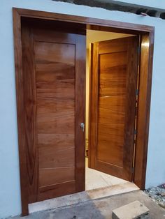 an open wooden door in front of a white wall with steps leading up to it