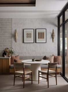 a dining room table with four chairs and two pictures hanging on the wall above it