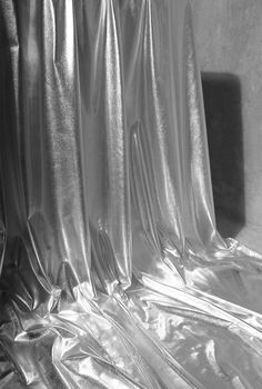 black and white photograph of shiny material covering the walls in a room with sunlight coming through it