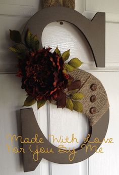 a door hanger decorated with burlock and flowers on the side of a white door