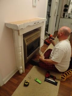 a man sitting on the floor working on a fireplace