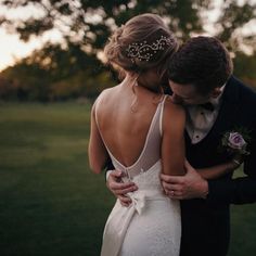 a bride and groom embracing each other in front of the sun setting on their wedding day