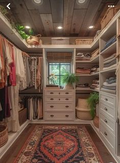 a walk in closet with lots of clothes and rugs on the floor next to it