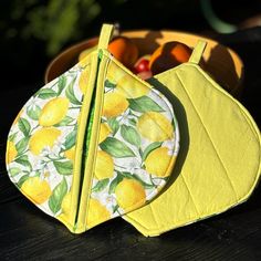 two bibs with lemons on them sitting next to some fruit in a bowl