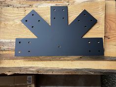 a metal arrow sign mounted to the side of a wooden wall with holes in it