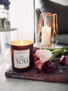 a candle sitting on top of a book next to flowers