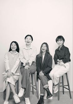 black and white photograph of four people sitting on stools smiling at the same person