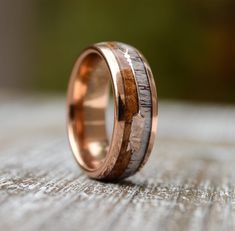 a wedding ring with wood inlays on top of a wooden table, close up