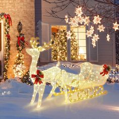 a lighted sleigh and reindeer in front of a house