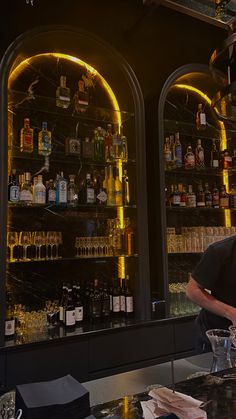 a man standing in front of a bar filled with liquor bottles