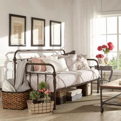 a day bed with white sheets and pillows in a living room area next to a window