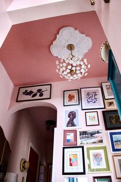 the ceiling is covered with many framed pictures and a chandelier hanging from it