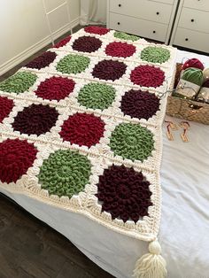 a crocheted blanket on top of a bed with white drawers and dressers in the background