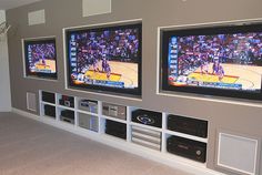 three large televisions mounted on the wall in a room with carpeted flooring