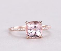 an engagement ring with a cushion cut pink sapphire and diamond accents on the band, set in 18k rose gold