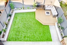 an aerial view of a small backyard with a green lawn and wooden decking area