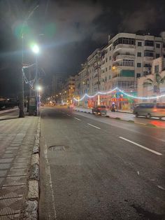 a city street at night with cars driving down it