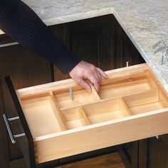 a person is placing nails in a drawer on a counter top with drawers underneath it