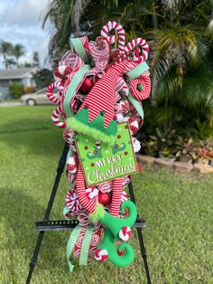 an outdoor christmas decoration with candy canes and green ribbon on a stand in the grass