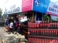 people are shopping at an outdoor market with bottles and bags on the side of the street