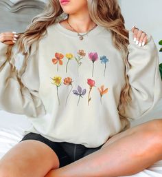 This simple pressed flowers themed long-sleeve sweatshirt fits like a cozy, well-loved favorite. It is a unisex-sized, medium-heavy fabric that is super soft, with a relaxed fit. Perfect for running errands or for a comfy night at home. The material is durable and comfortable with a 50% cotton and 50% polyester blend and no uncomfortable side seams. * 50% cotton/50% polyester * Medium-heavy fabric * Loose fit * Runs true to size * Sewn in tag * Gildan 18000 Care Instructions: Machine wash: warm Cozy Long Sleeve Sweater With Floral Print, Cotton Floral Print Long Sleeve Sweater, Cozy Spring Sweater With Letter Print, Cozy Letter Print Sweater For Spring, White Tops With Plant Print For Fall, Floral Print Long Sleeve Sweatshirt For Fall, Spring Floral Print Long Sleeve Sweater, Cozy Long Sleeve Sweatshirt For Spring, Long Sleeve Floral Print Sweater For Spring