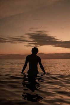 a man standing in the water at sunset