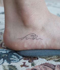 a foot with a small wave tattoo on it