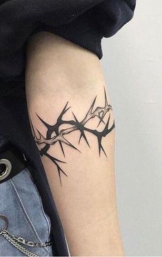 a black and white photo of a tattoo with barbed wire on the side of a woman's arm