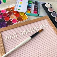 some paint and brushes are sitting on a table next to a sign that says just swatch me