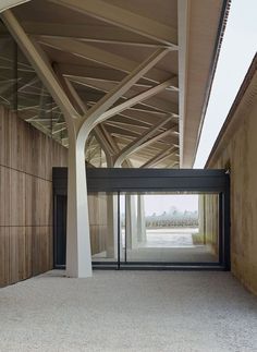 the inside of a building with wooden walls and columns on both sides, looking into an open space