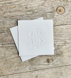 two white cards with the word monogrammed on them sitting on a wooden table