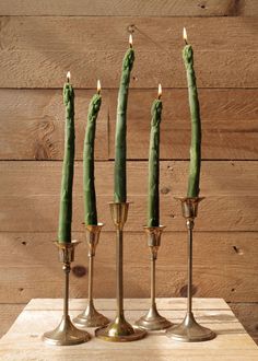 three brass candlesticks with green beans in them