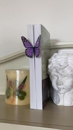 a bookend with a butterfly sitting on top of it next to a candle holder