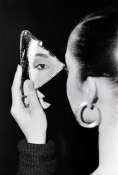 a woman is looking at her face in the mirror while holding it up to her face