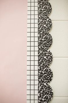 three pieces of black and white paper on a pink wall next to a grid pattern