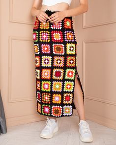 a woman standing in front of a wall wearing a long crochet skirt and white top