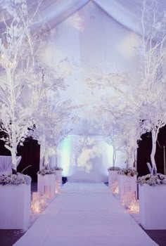 the aisle is decorated with white trees and candles