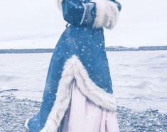 a woman dressed in blue and white standing on the beach