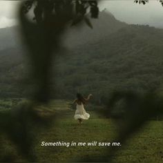 a woman in a white dress standing on top of a lush green field under a cloudy sky