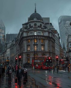 a red double decker bus driving down a street next to tall buildings on a rainy day