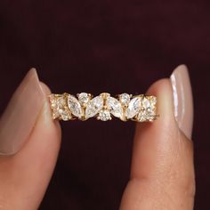 a woman's hand holding a gold ring with five pear shaped diamonds on it