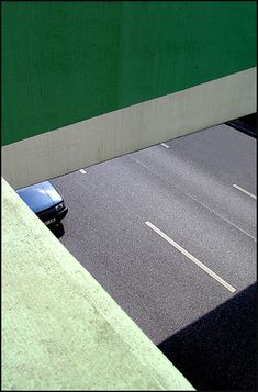 a car driving down a street next to a green wall