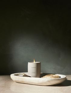 a white candle sitting on top of a bowl