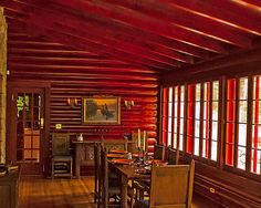 a dining room with wooden floors and red walls, along with large windows that look out onto the outdoors