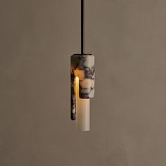 a white and black light hanging from a ceiling fixture with a candle in the middle