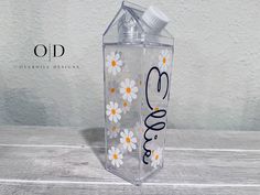 a clear bottle with white daisies and the word love on it