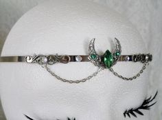 Crescent Moon Circlet This beautiful circlet has a sterling silver plated filigree crescent moon with emerald green faceted glass setting, sterling silver plated filigree accents, rhinestones and metal chain. Adjustable. Handmade Silver Fantasy Body Jewelry, Silver Fantasy Body Jewelry For Gift, Silver Fantasy Jewelry For Festivals, Adjustable Silver Jewelry For Fantasy Events, Silver Bohemian Jewelry For Fantasy Events, Nickel-free Fantasy Jewelry For Festivals, Fantasy Crown Shape Jewelry For Gifts, Fantasy Crown-shaped Jewelry Gift, Fantasy Crown Jewelry For Gifts