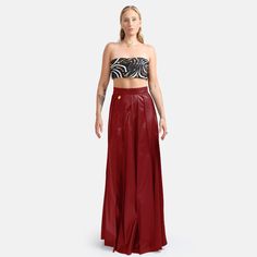 A hand pleated maxi skirt in red vegan leather featuring hidden zip closure and stylish golden embellishment. The lightweight fabric provides a relaxed, yet structured drape with a degree of stretch for added comfort and durability. The vertical pleating elongates the lower body for an elegant silhouette. An excellent choice for an stylish occasion where comfort is appreciated.  Made to order by qualified artisans in Australia. Organically Styled Hand Pleats  Maxi Length 60% PU 35% Polyester 5% Spandex Vegan Leather Sustainably Made in Australia Dry Clean Luxury Long Skirt For Party, Luxury Flared Skirt For Party, Luxury Flared Party Skirt, Luxury Red Fitted Bottoms, Luxury Fitted Red Bottoms, Luxury Skirt For Gala, Luxury Long Skirt For Gala, Luxury Evening Mini Skirt, Elegant High Waist Red Skirt