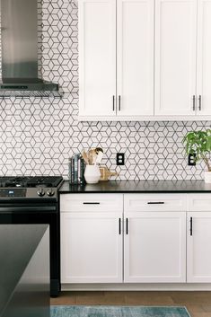 a kitchen with white cabinets, black counter tops and stainless steel stove top oven in the center