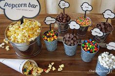 an assortment of popcorn in buckets on a wooden table with paper speech bubbles above them